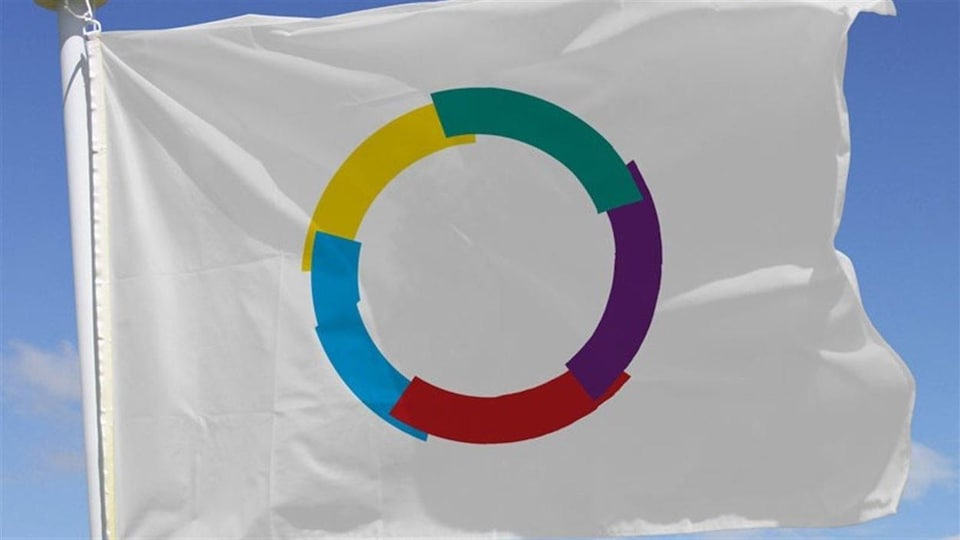 Le drapeau de l'organisation internationale de la francophonie flotte au vent sous un ciel bleu.