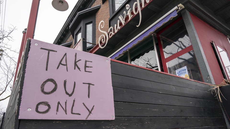 Une affiche dit « mets à emporter seulement » devant un restaurant.