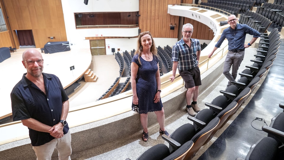 Les quatre responsables sont debout sur le balcon d'une salle de concert.