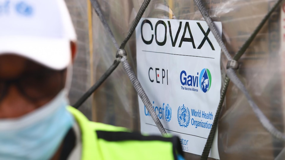 Une personne à côté d'un paquet étiqueté COVAX. 