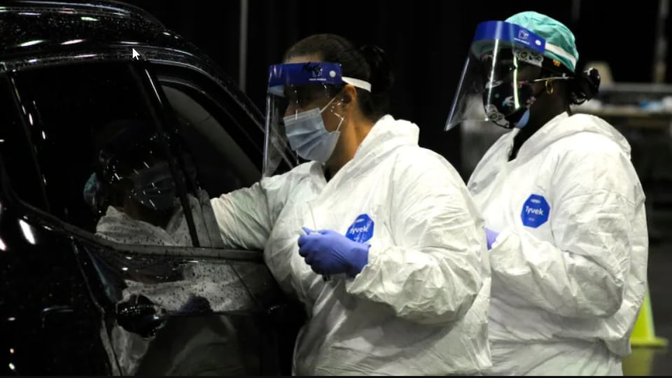 Deux travailleuses de la santé effectuent un test de dépistage de COVID-19 à Mobile, en Alabama.