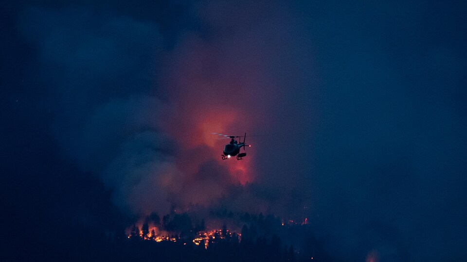 Un hélicoptère survole un feu de forêt brûlant à Lytton, en Colombie-Britannique.