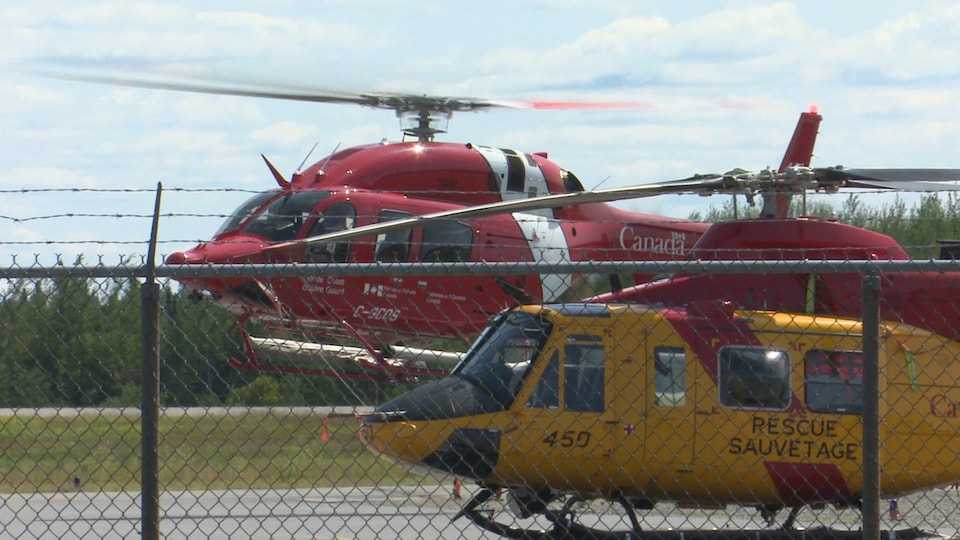 Un hélicoptère de la Garde côtière et un hélicoptère de l'Aviation royale canadienne sur une piste d'aéroport.