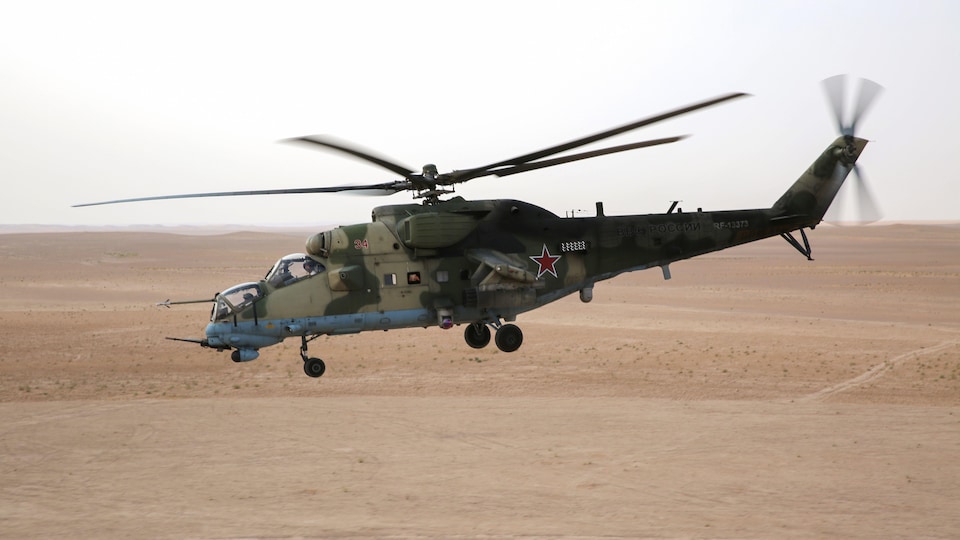 Un hélicoptère militaire survole un désert.
