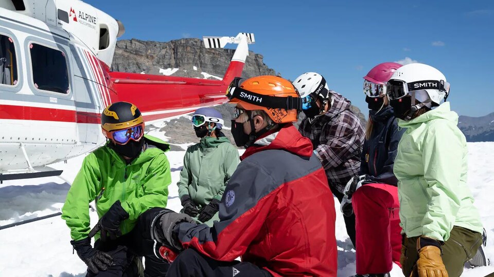 Des skieurs à proximité d'un hélicoptère.