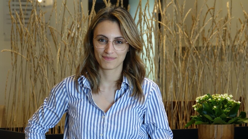 A woman in her thirties wearing glasses.
