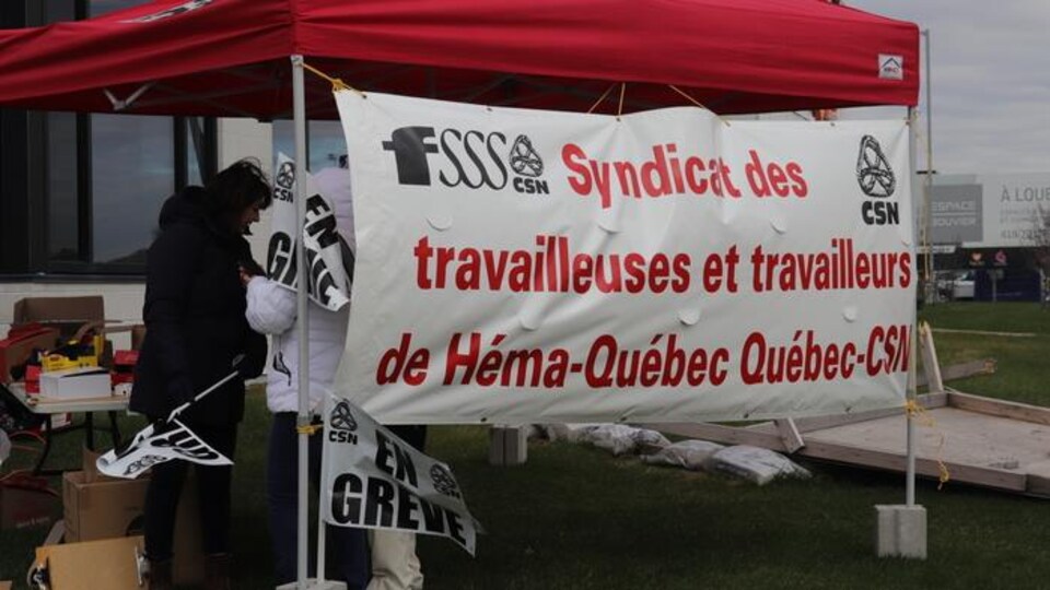 Pancarte représentant le syndicat des employés de Québec devant une tente.
