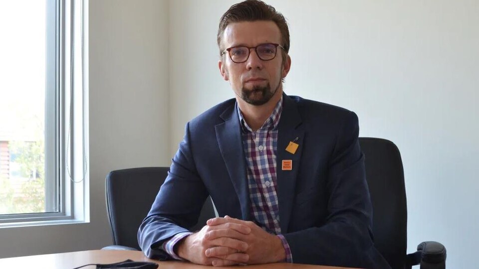 Henry Wall, directeur général du Conseil des services du district de Kenora, assis à un bureau.