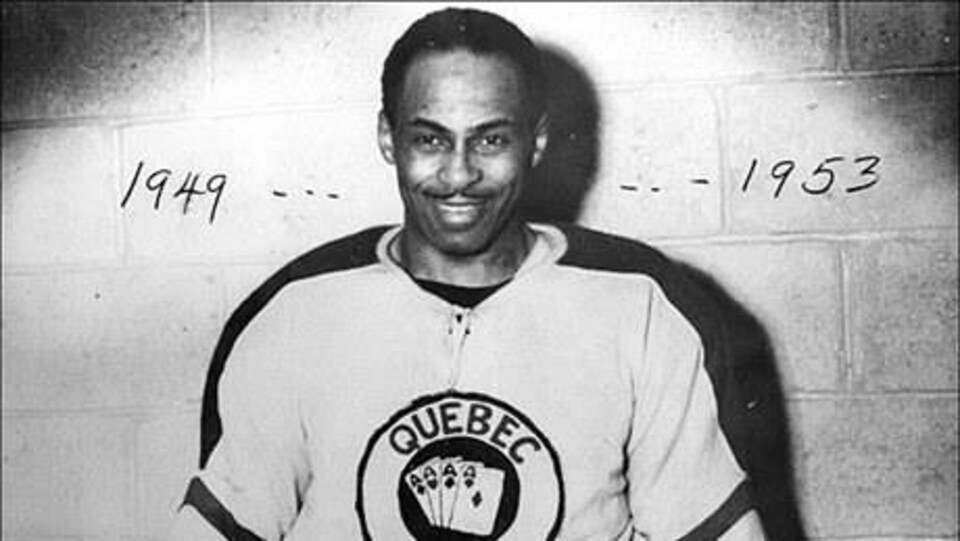Photo d'époque, remontant aux années 50, représentant le hockeyeur torontois d'ascendance jamaïcaine Herbert Carnegie endossant l'uniforme des As de Québec