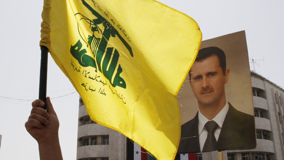 Un drapeau du Hezbollah flottant devant un portrait du président syrien Bachar Al-Assad.