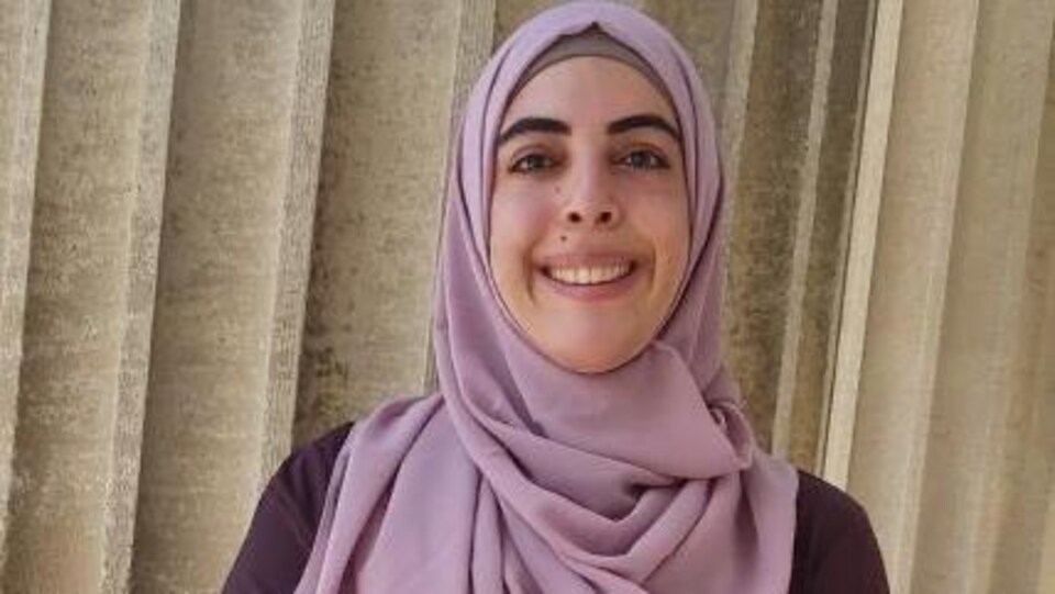 Portrait d'une jeune femme souriante. Elle porte un foulard.