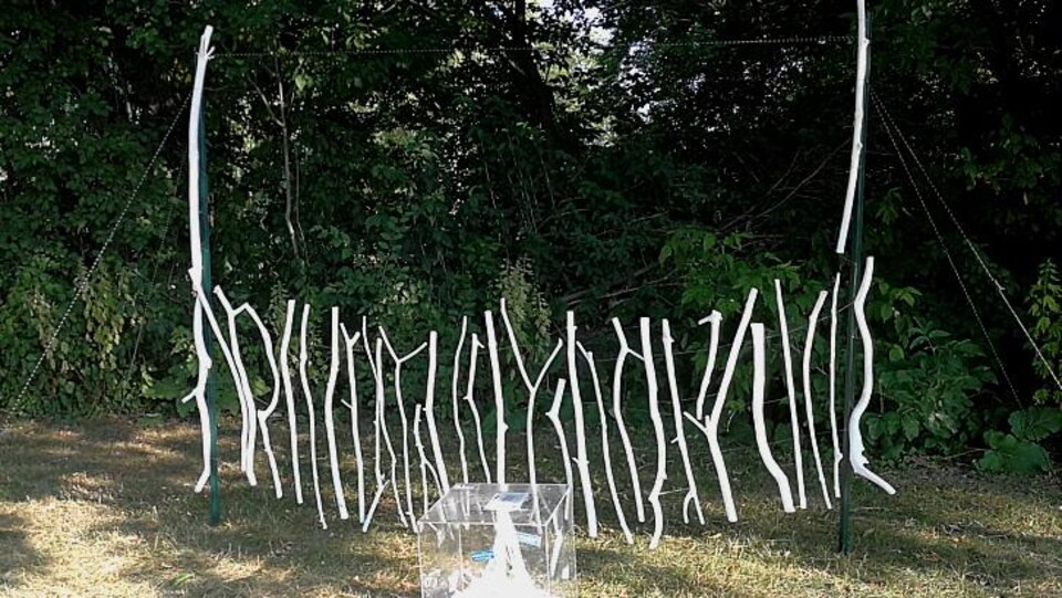 Une oeuvre constituée de branches peintes en blanc, dont la partie supérieure a disparu.