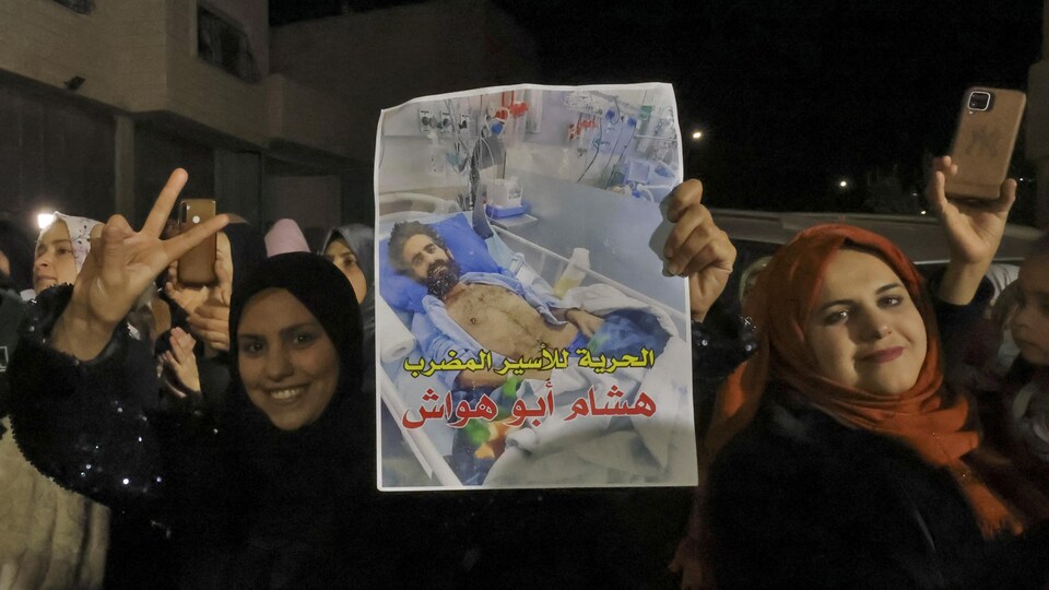 Des femmes brandissant une affiche représentant un homme sur un lit d'hôpital.
