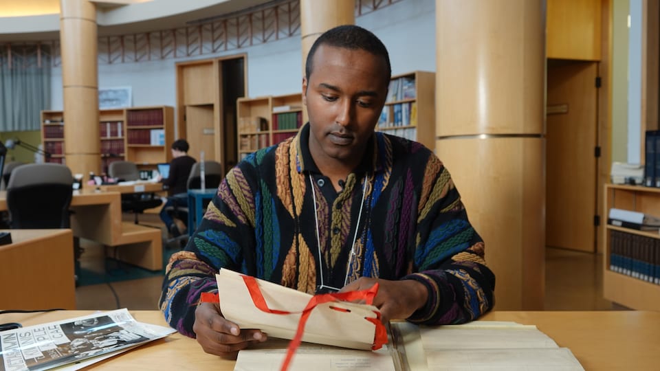 Plan large de Bashir Mohamed assis aux archives provinciales. 