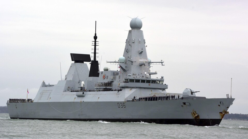 Le HMS Defender navigue près d'un port.