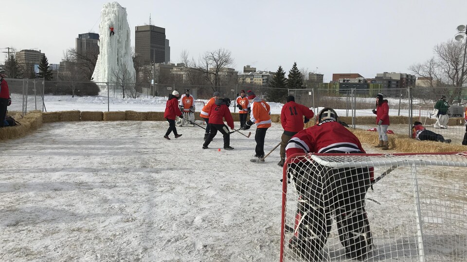 Des joueurs de hockey bottine jouent à l'extérieur avec une balle et des bâtons de hockey.
