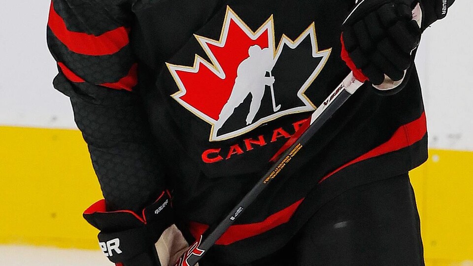 Plan rapproché du chandail de hockey noir d'Équipe Canada junior décoré du logo de Hockey Canada.