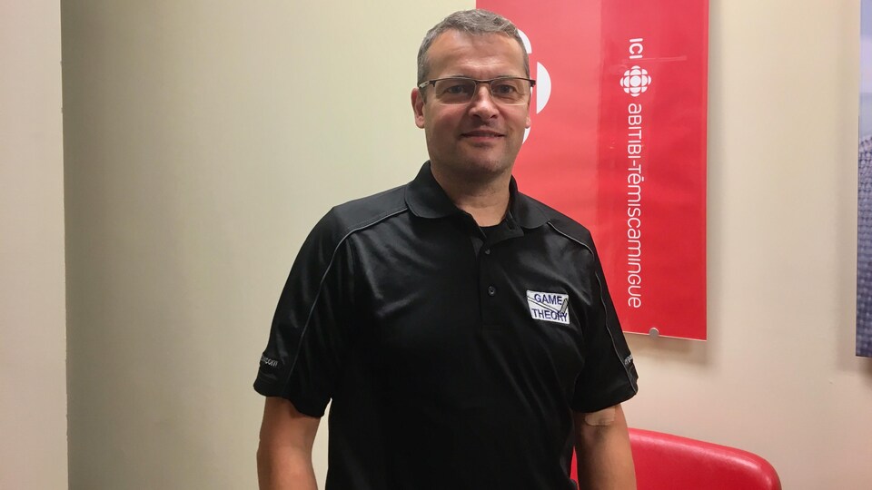 Benoît Tremblay pose devant une affiche de Radio-Canada Abitibi-Témiscamingue.