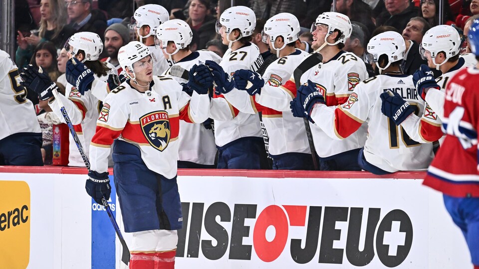 Il donne la main à ses coéquipiers au banc.