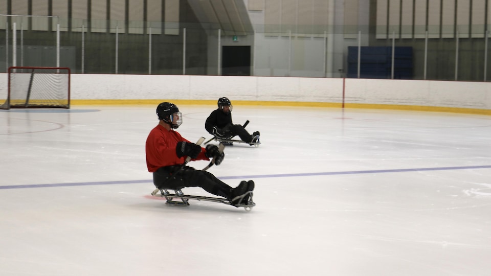 Deux joueurs de hockey luge en action sur la glace.