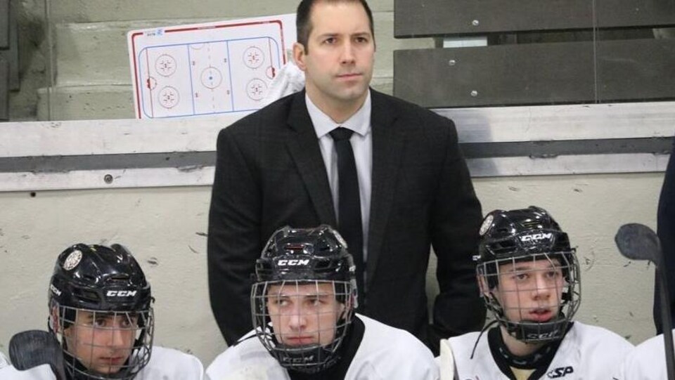 L'entraîneur de hockey derrière le banc des joueurs.