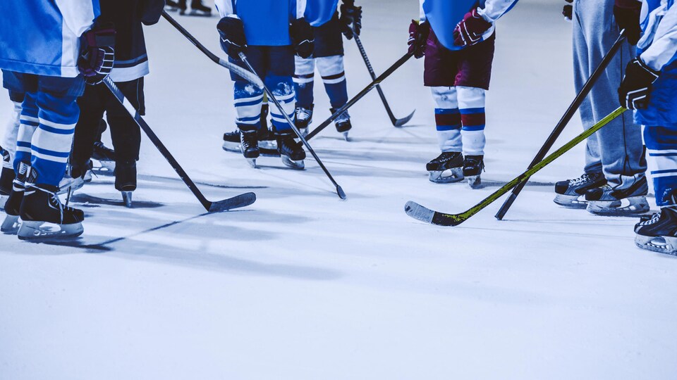 Les patins et les bâtons de jeunes joueurs de hockey sur une patinoire.