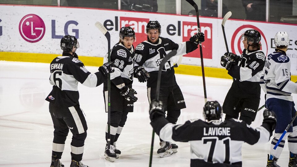 Des joueurs de l'Armada de Blainville-Boisbriand célèbrent sur la patinoire après un but.