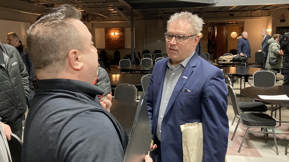 Un homme de dos discute avec Claude Bouchard.