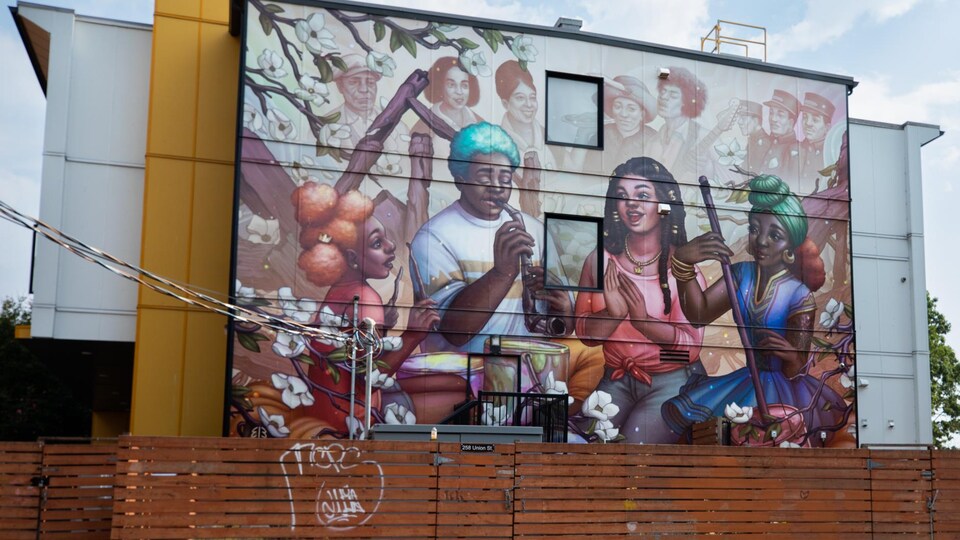 Murale qui montre quatre personnes jouant de la musique et, en arrière-plan, des visages de personnalités connues de la communauté noire.