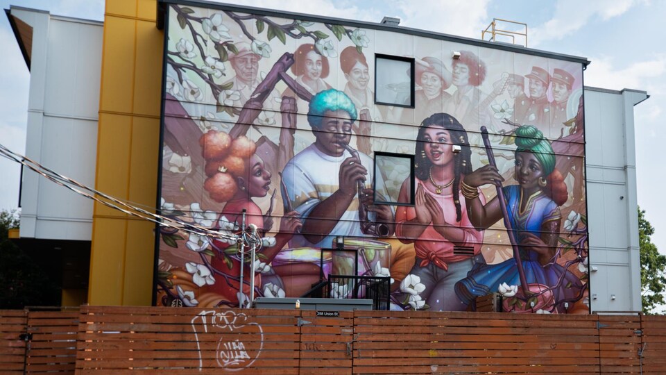 Une murale qui dépeint quatre personnes jouant de la musique et en arrière-plan des visages de personnalités connues de la communauté.