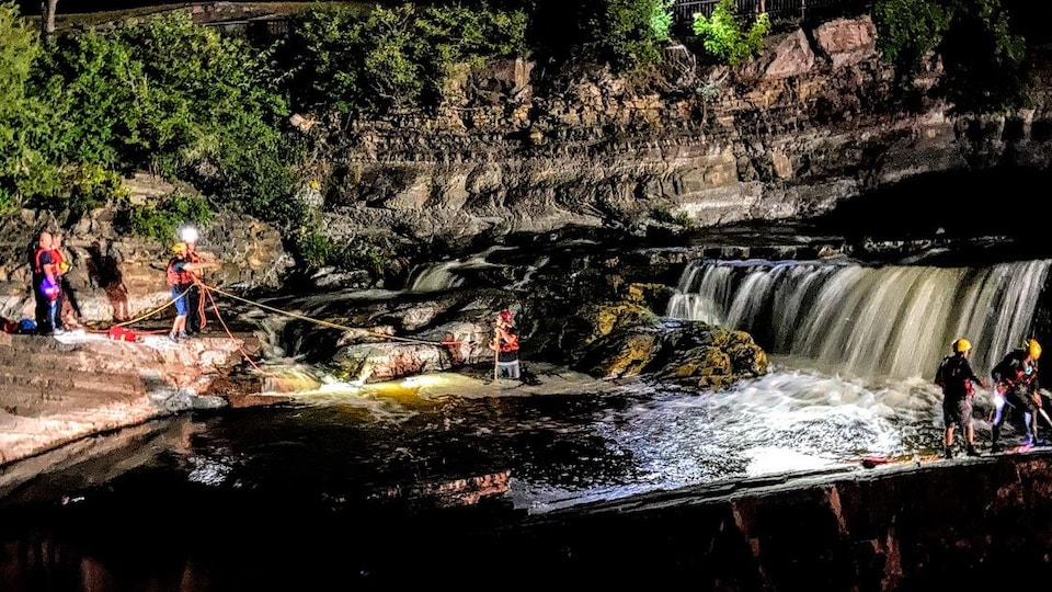 Des membres de l'équipe de sauvetage près d'un cours d'eau la nuit.