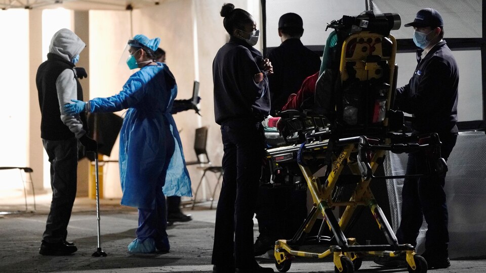 Des malades devant un hôpital accueillis par le personnel médical