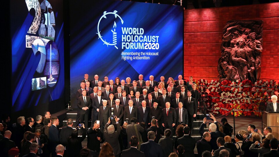 Une cinquantaine de personnes prennent la pose devant un écran où il est écrit Forum mondial sur la Shoah 2020.