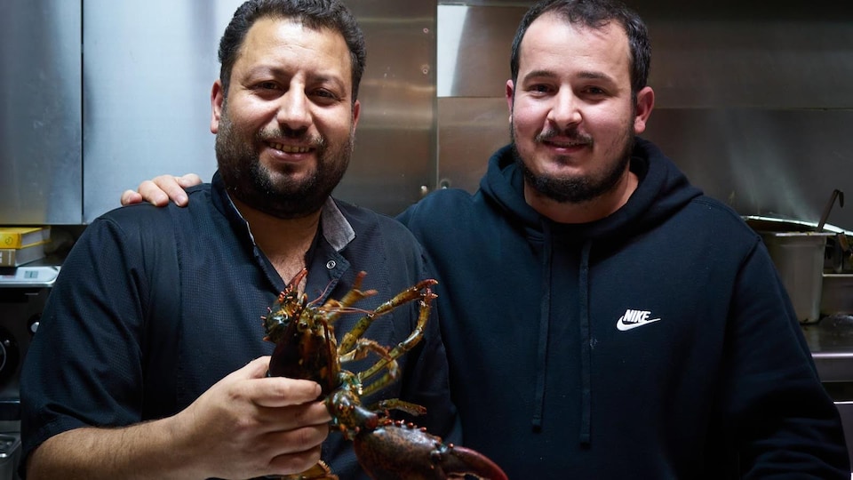 Le chef cuisinier tient un homard entre ses mains.