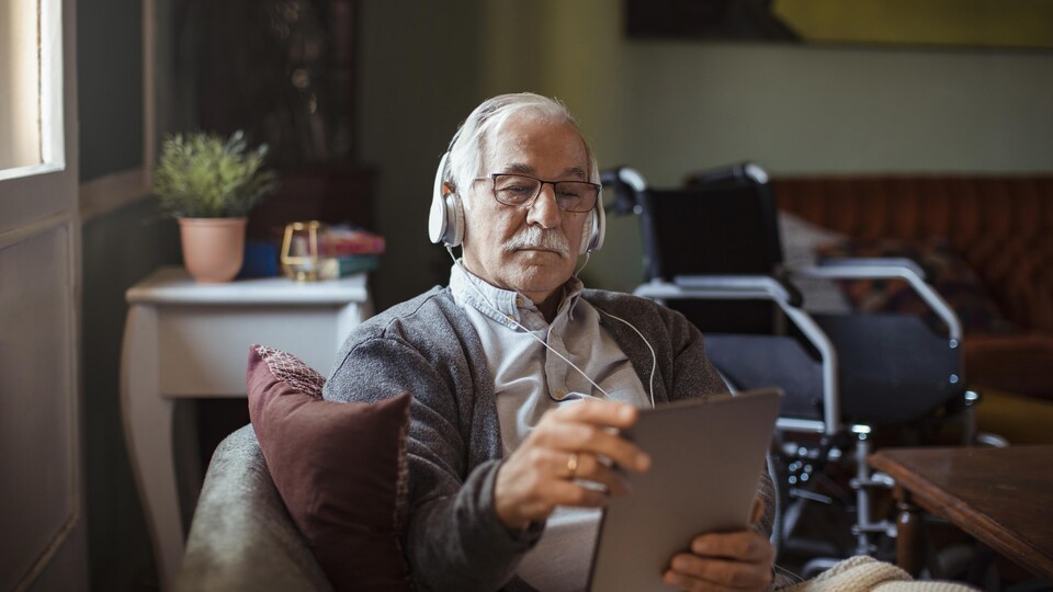 Un homme âgé écoute de la musique à partir de sa tablette.