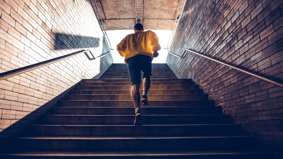 Un homme monte un escalier en courant.