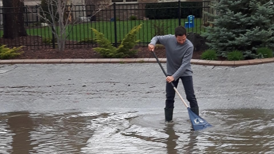 Un homme a les pieds dans l'eau et tient un balais.