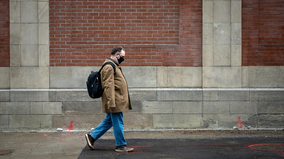 Un homme portant un masque marche au centre-ville d'Ottawa.