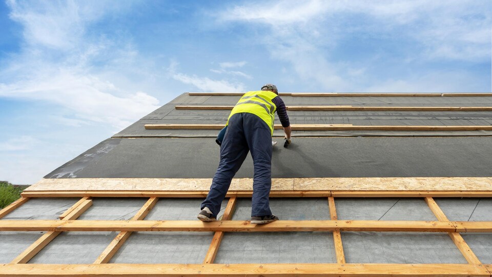 Un homme rénove le toit d'une maison.