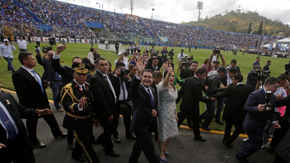 Le président accompagné de sa femme salue la foule dans un stade de soccer de la capitale.