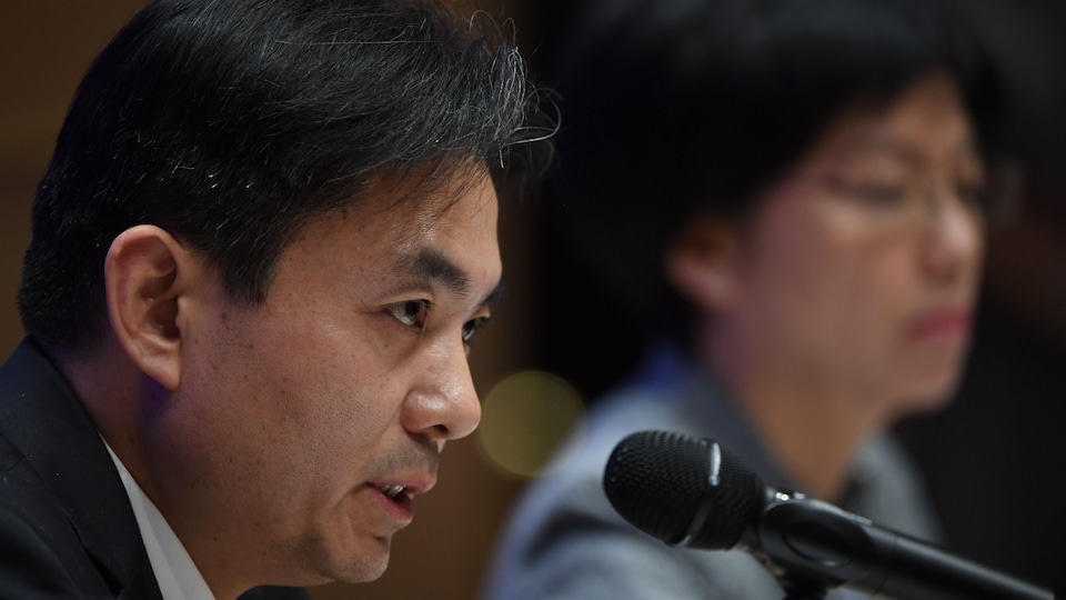 Yang Guang devant un micro, avec au second plan la dirigeante de l'exécutif local, Carrie Lam.