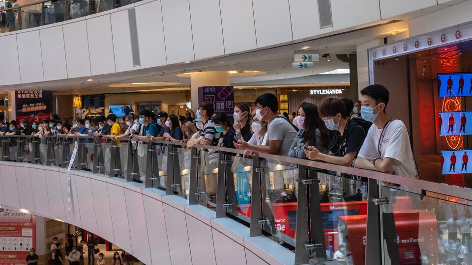 Des manifestants portant des masques de protection se rassemblent dans un centre commercial.