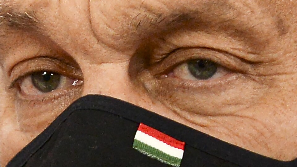 Gros plan des yeux du premier ministre hongrois Viktor Orban. Il porte un masque sur lequel figure le drapeau de la Hongrie.