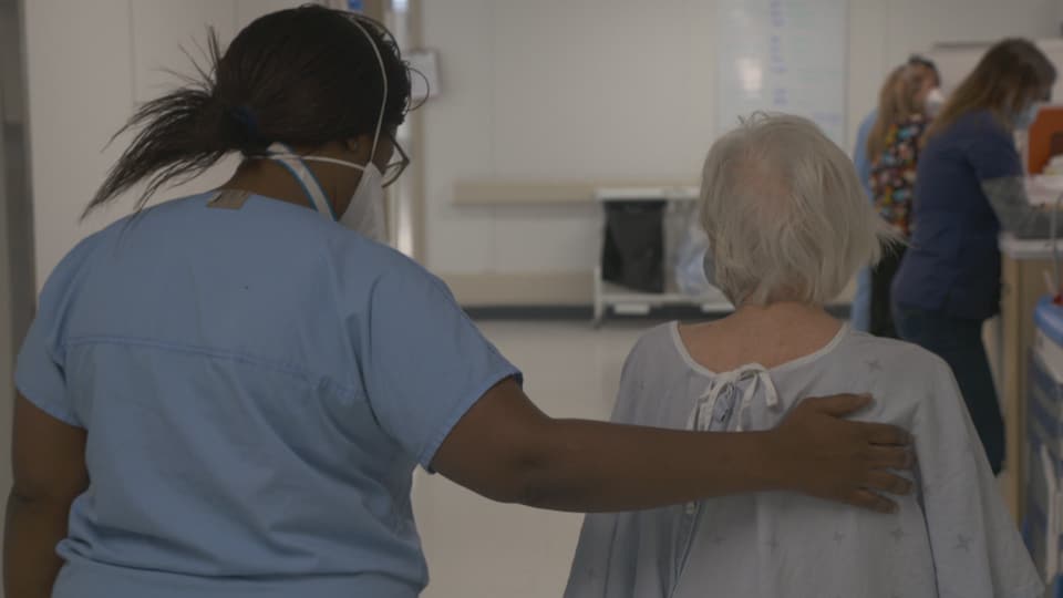 Une infirmière marche avec une patiente.