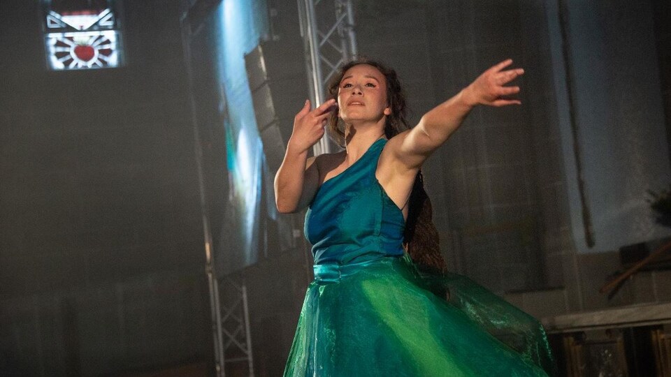 Une danseuse fait une chorégraphie sur scène. 