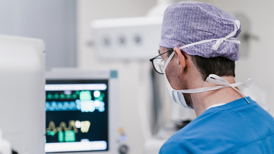 Un anesthésiste surveille l'état de santé d'un patient sur un écran en salle d'opération à l'hôpital. 