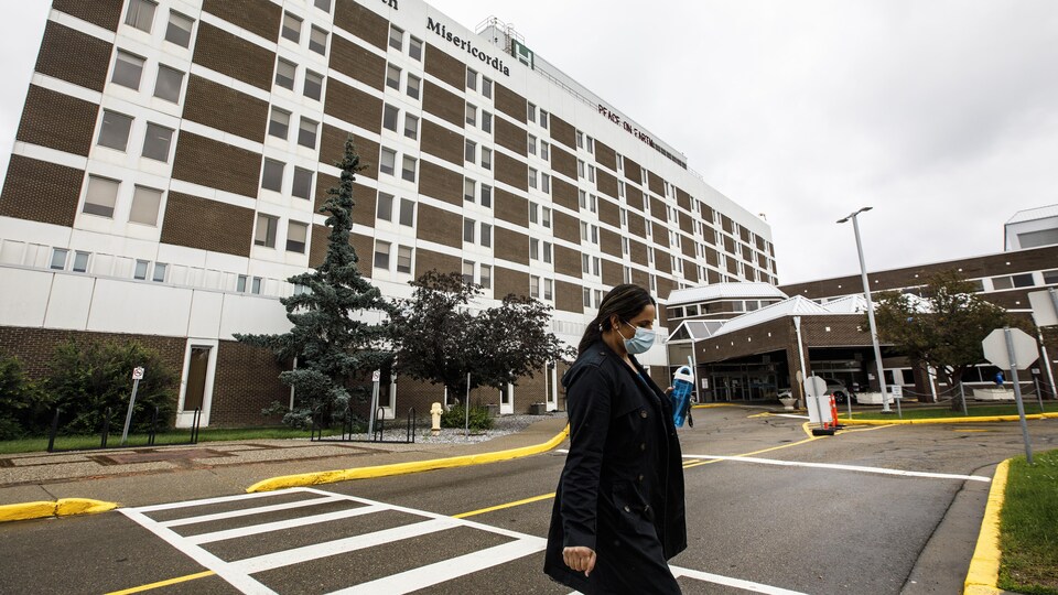Une femme avec un masque sort d'un hôpital.