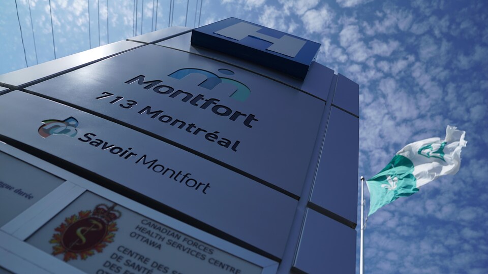 Un panneau de l'Hôpital Montfort près d'un drapeau franco-ontarien battant au vent.