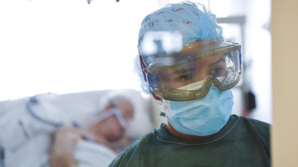 Une infirmière porte des lunettes de protection et un masque.