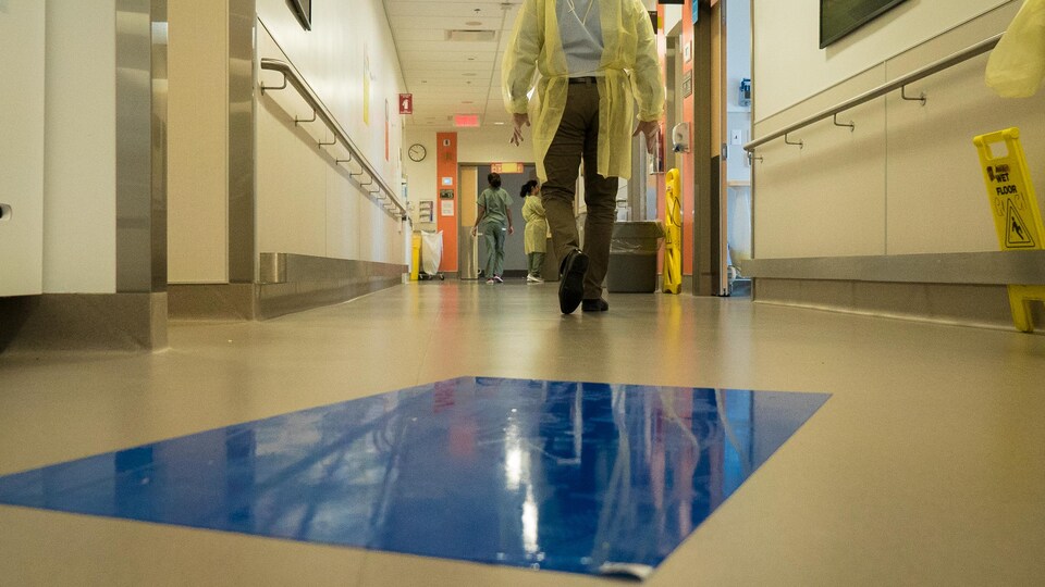 Un tapis de décontamination est installée dans un corridor d’hôpital.
